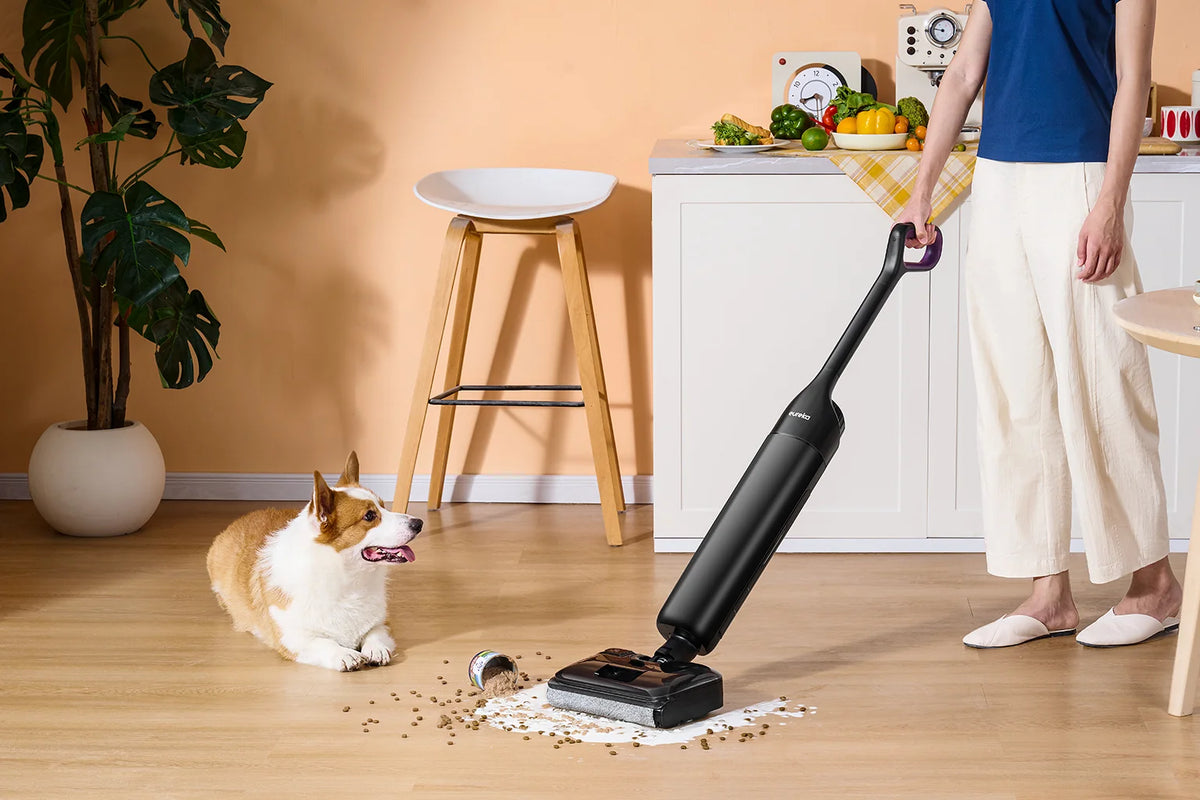 Familia y un spaniel en una cocina luminosa con un robot aspirador Eureka cerca
